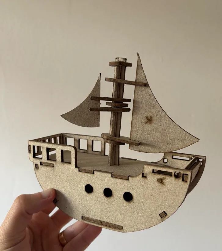 Mão segurando o Barco Voador montado em MDF, o projeto integrador do 1º ano